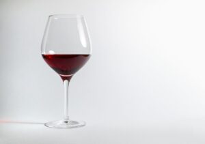 Kieliszek wytrawnego czerwonego wina z niewielką ilością płynu na czystym, białym tle, ilustrujący "najlepszy wybór" alkoholu o najmniejszej zawartości cukru; alkohol a cukrzyca typu 1