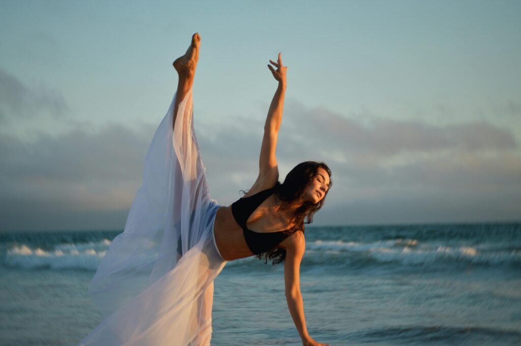 Kobieta tańcząca na plaży o zachodzie słońca, symbolizująca wolność od presji wyników na wadze. Podejście, które promuje dietetyk cukrzyca typu 1.