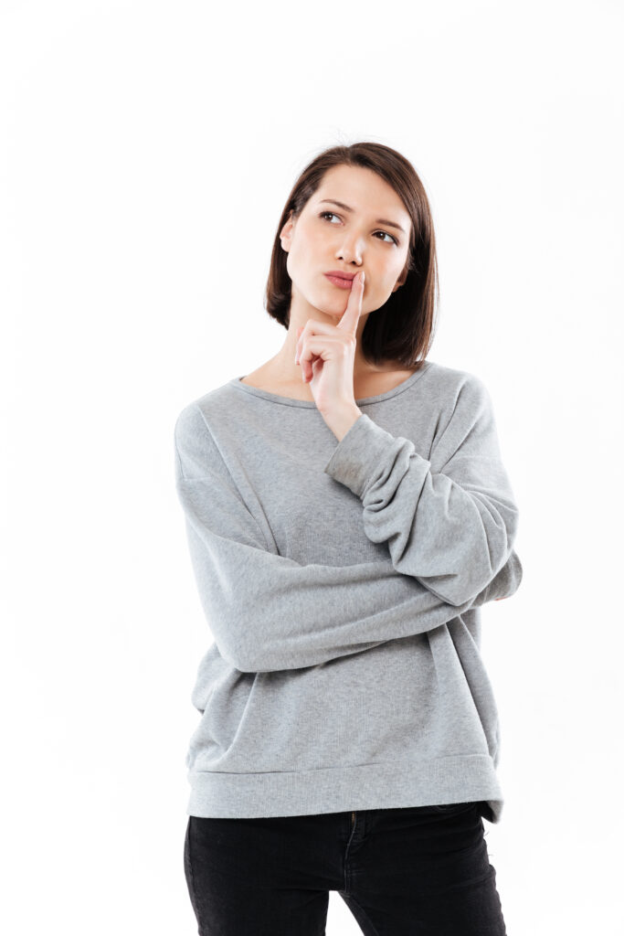 Zastanawiająca się kobieta w szarej bluzie rozważająca, czy pierwsza konsultacja dietetyczna pomoże jej w opanowaniu cukrzycy, IO i otyłości oraz czy dietetyk w cukrzycy jest dla niej.